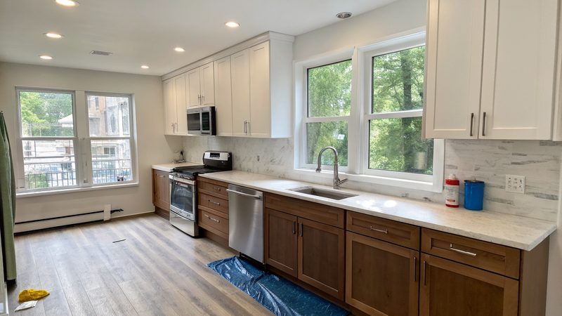 Newly renovated apartment kitchen with white upper and walnut lower cabinets, just after construction
